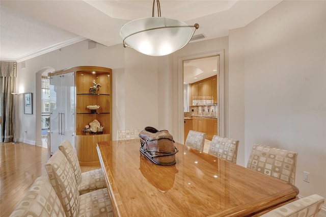 dining space featuring ornamental molding and light hardwood / wood-style floors