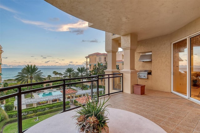 balcony at dusk with a water view, a swimming pool, and a grill