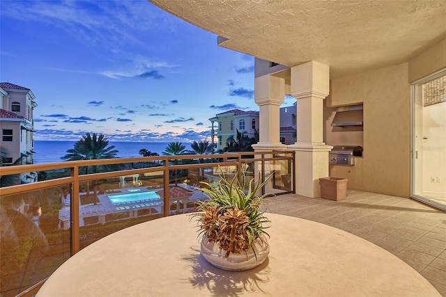 balcony at dusk with a water view and grilling area