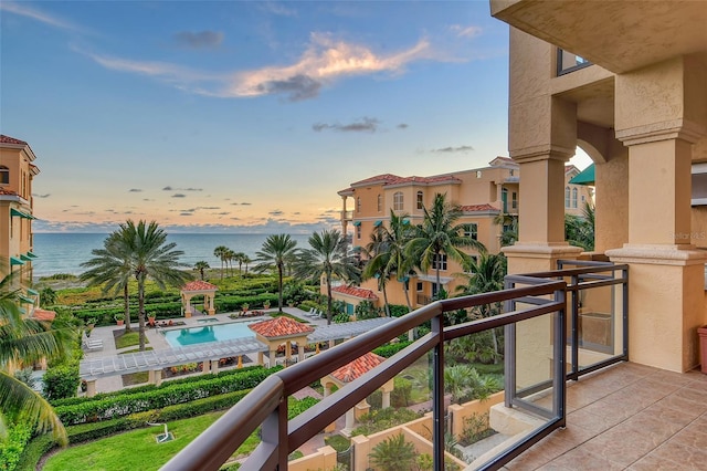 balcony at dusk featuring a water view