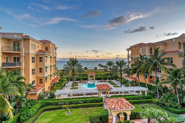 view of community featuring a pergola, a swimming pool, a lawn, and a water view