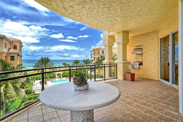 balcony with grilling area, exterior kitchen, and a water view