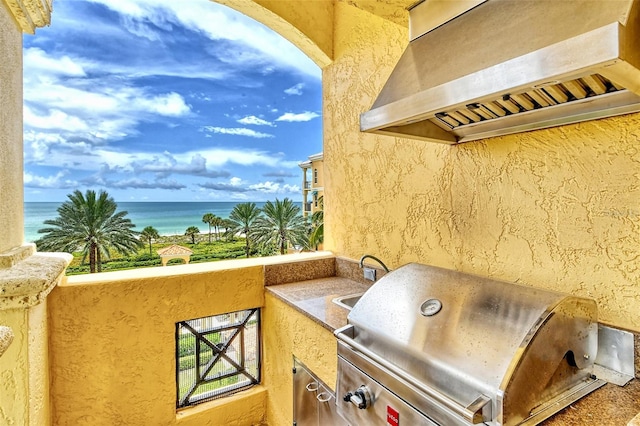 balcony with area for grilling, sink, exterior kitchen, and a water view