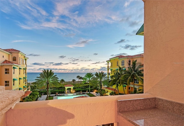 balcony at dusk featuring a water view