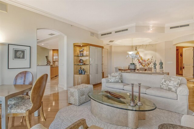 living room with light wood-type flooring and crown molding