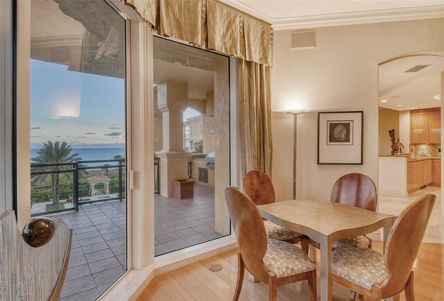 dining space with a wealth of natural light, a water view, crown molding, and light hardwood / wood-style floors