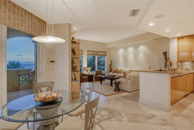 dining room featuring sink, vaulted ceiling, and light tile patterned floors