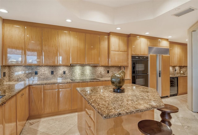 kitchen with tasteful backsplash, light tile patterned floors, beverage cooler, a center island, and black appliances