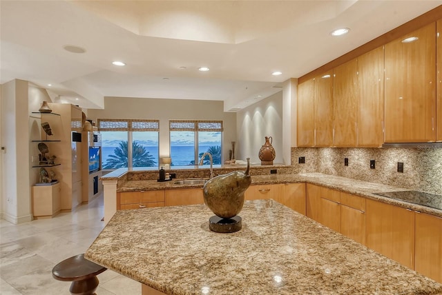 kitchen with decorative backsplash, light stone countertops, sink, and kitchen peninsula