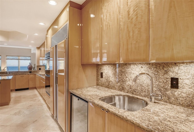 kitchen featuring light stone counters, sink, tasteful backsplash, and light brown cabinetry