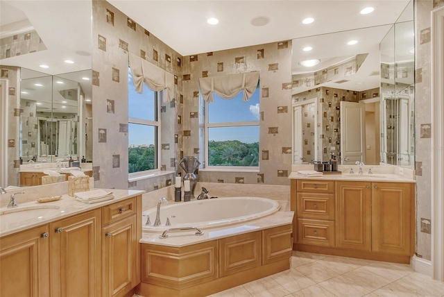 bathroom featuring tiled tub, dual vanity, and tile patterned flooring