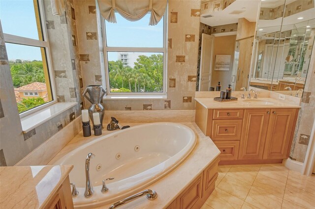 bathroom featuring a relaxing tiled tub, tile patterned floors, vanity, and a healthy amount of sunlight