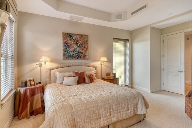 bedroom with a tray ceiling and light colored carpet