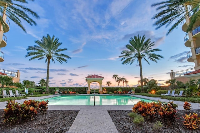 pool at dusk with a patio area