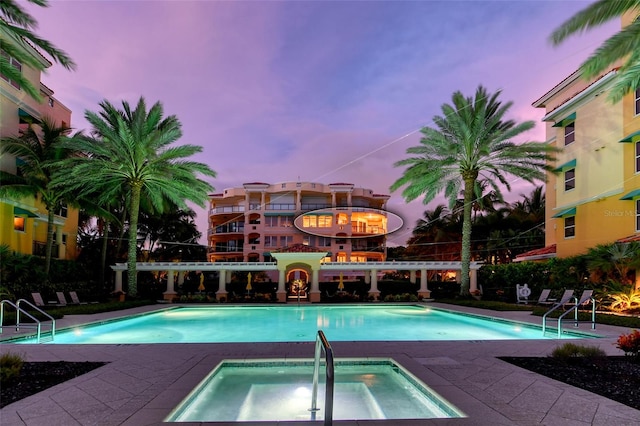 pool at dusk with a hot tub