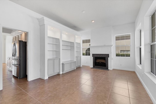 unfurnished living room with tile patterned flooring, built in shelves, and a fireplace