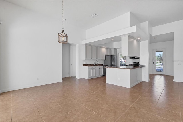 kitchen featuring white cabinets, a towering ceiling, decorative light fixtures, kitchen peninsula, and stainless steel appliances