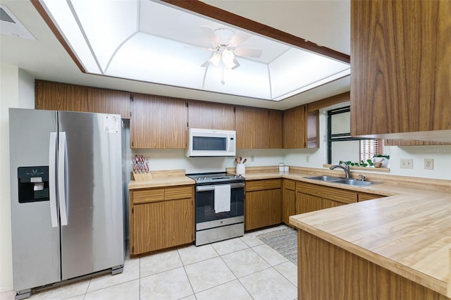 kitchen with sink, ceiling fan, light tile patterned floors, appliances with stainless steel finishes, and kitchen peninsula