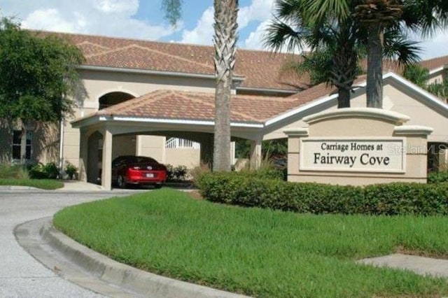 community sign featuring a carport and a lawn