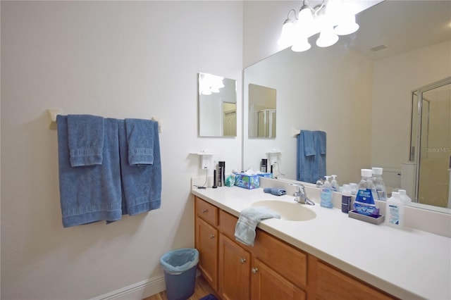 bathroom featuring vanity, a shower with door, and a notable chandelier