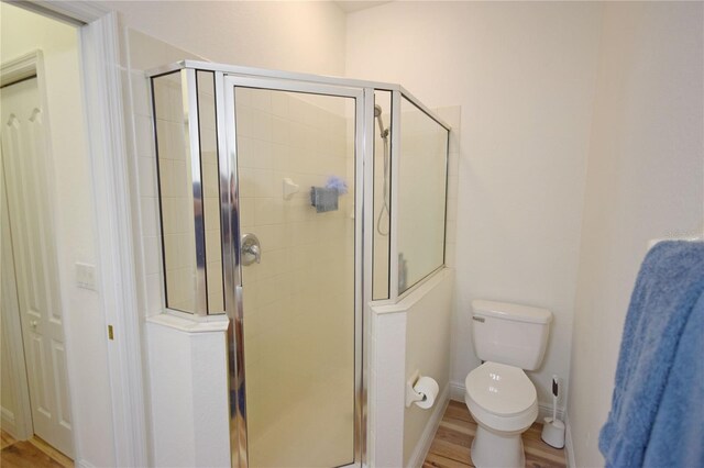 bathroom with wood-type flooring, toilet, and an enclosed shower