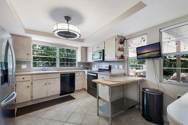 kitchen with a raised ceiling, sink, light tile patterned flooring, and appliances with stainless steel finishes