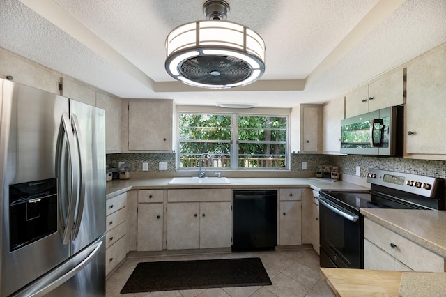 kitchen with light tile patterned floors, stainless steel appliances, a raised ceiling, and sink