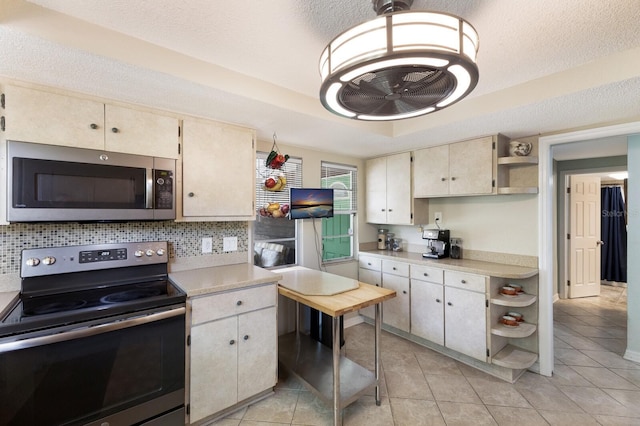 kitchen featuring stainless steel appliances, a raised ceiling, backsplash, a textured ceiling, and light tile patterned flooring