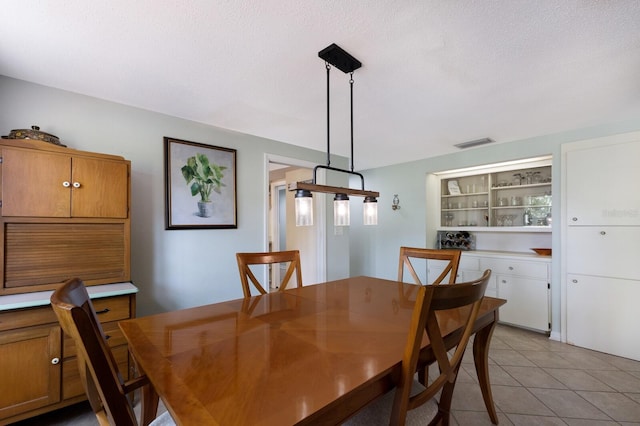 tiled dining space featuring a textured ceiling