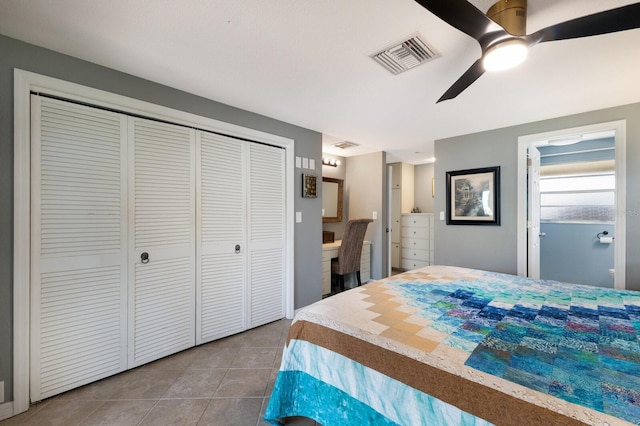 bedroom with a closet, connected bathroom, ceiling fan, and tile patterned flooring