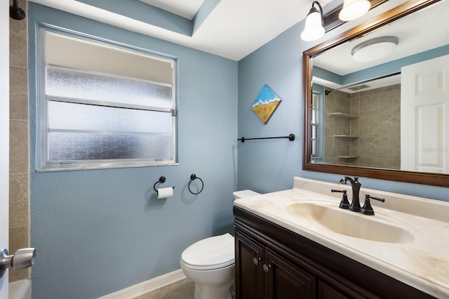 bathroom with a tile shower, vanity, and toilet