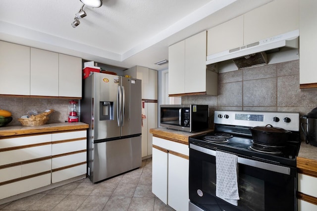 kitchen with white cabinetry, range hood, decorative backsplash, light tile patterned floors, and appliances with stainless steel finishes