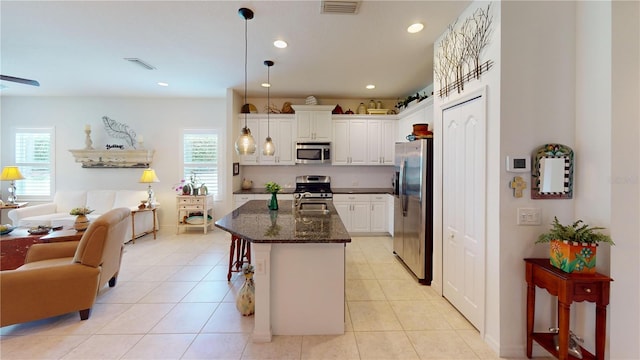 kitchen featuring decorative light fixtures, stainless steel appliances, white cabinets, light tile floors, and a breakfast bar