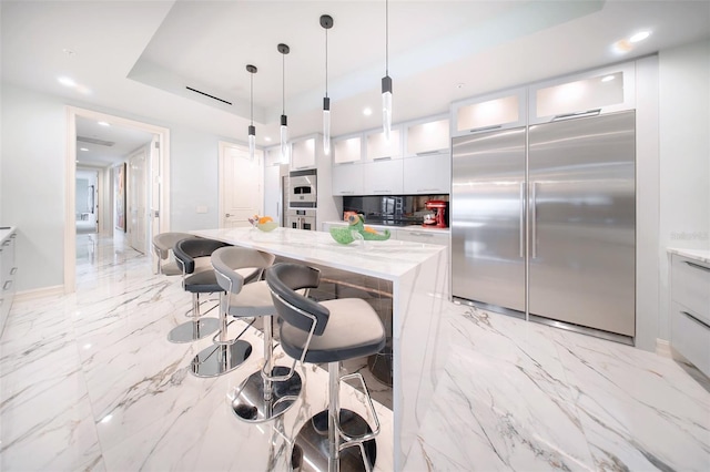 kitchen featuring white cabinets, light stone counters, and built in refrigerator