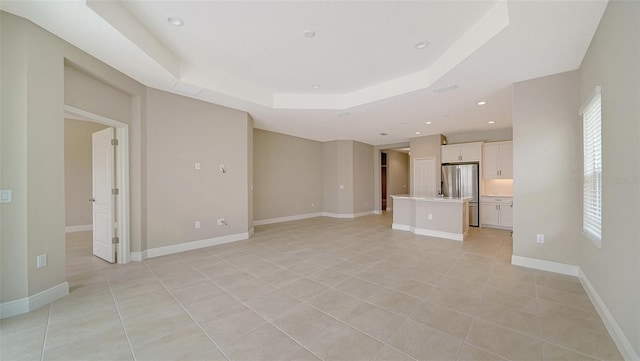 unfurnished living room featuring a raised ceiling and light tile patterned floors