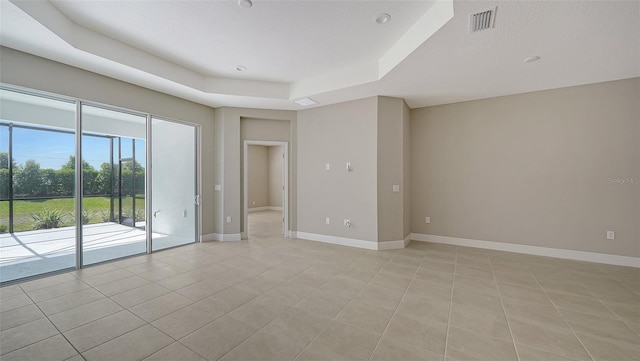 tiled spare room featuring a tray ceiling