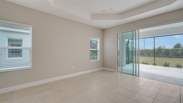 spare room with a raised ceiling and light tile patterned floors