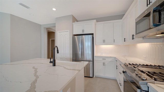 kitchen with white cabinetry, light tile patterned flooring, tasteful backsplash, and stainless steel appliances