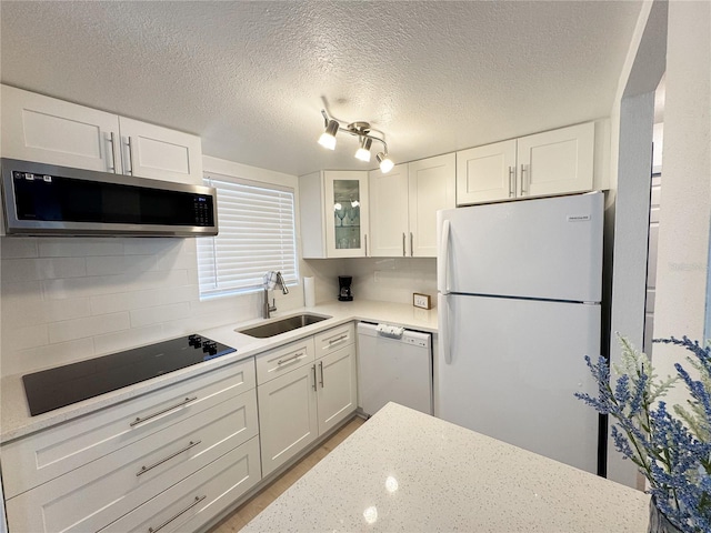 kitchen featuring tasteful backsplash, glass insert cabinets, white cabinets, a sink, and white appliances