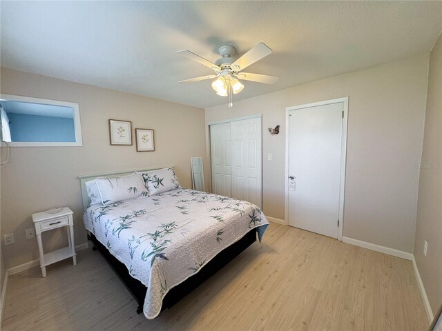 bedroom featuring light wood-type flooring, a closet, baseboards, and a ceiling fan