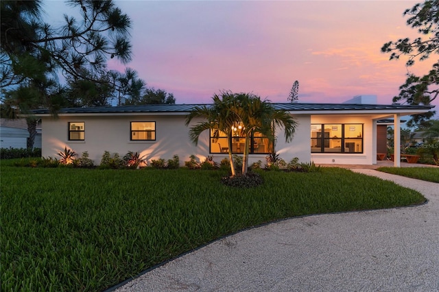 ranch-style home featuring a carport and a yard