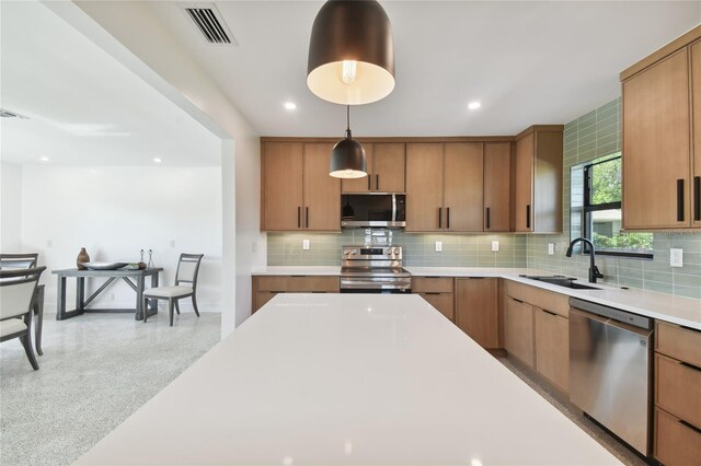 kitchen with stainless steel appliances, hanging light fixtures, sink, and backsplash