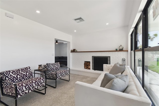 living room featuring ceiling fan, a fireplace, and light carpet