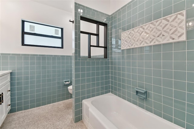 full bathroom featuring tile walls, tiled shower / bath combo, vanity, and toilet