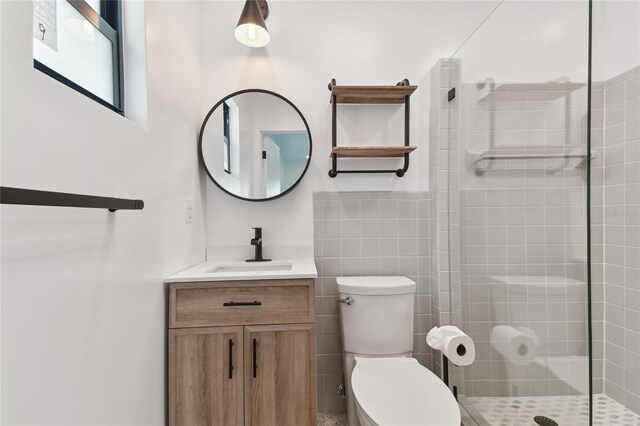 bathroom featuring vanity, toilet, tile walls, and a shower with door