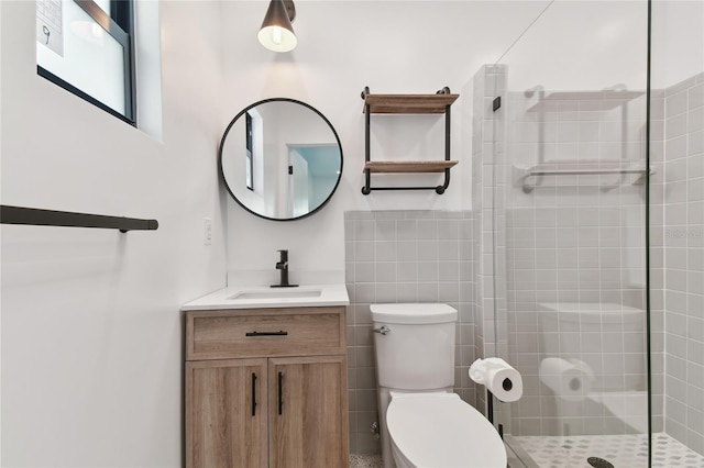 bathroom featuring vanity, tile walls, toilet, and a tile shower