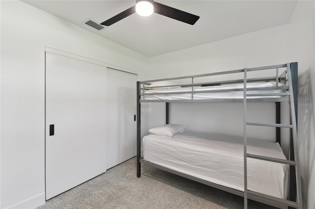 carpeted bedroom featuring ceiling fan and a closet