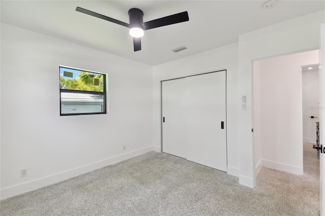 unfurnished bedroom with light colored carpet, a closet, and ceiling fan