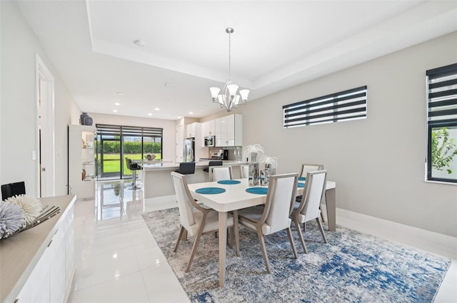 tiled dining space featuring an inviting chandelier and a tray ceiling