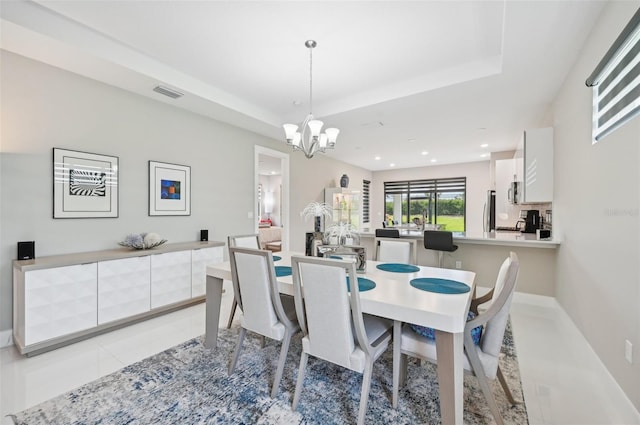 tiled dining space featuring a raised ceiling and a notable chandelier